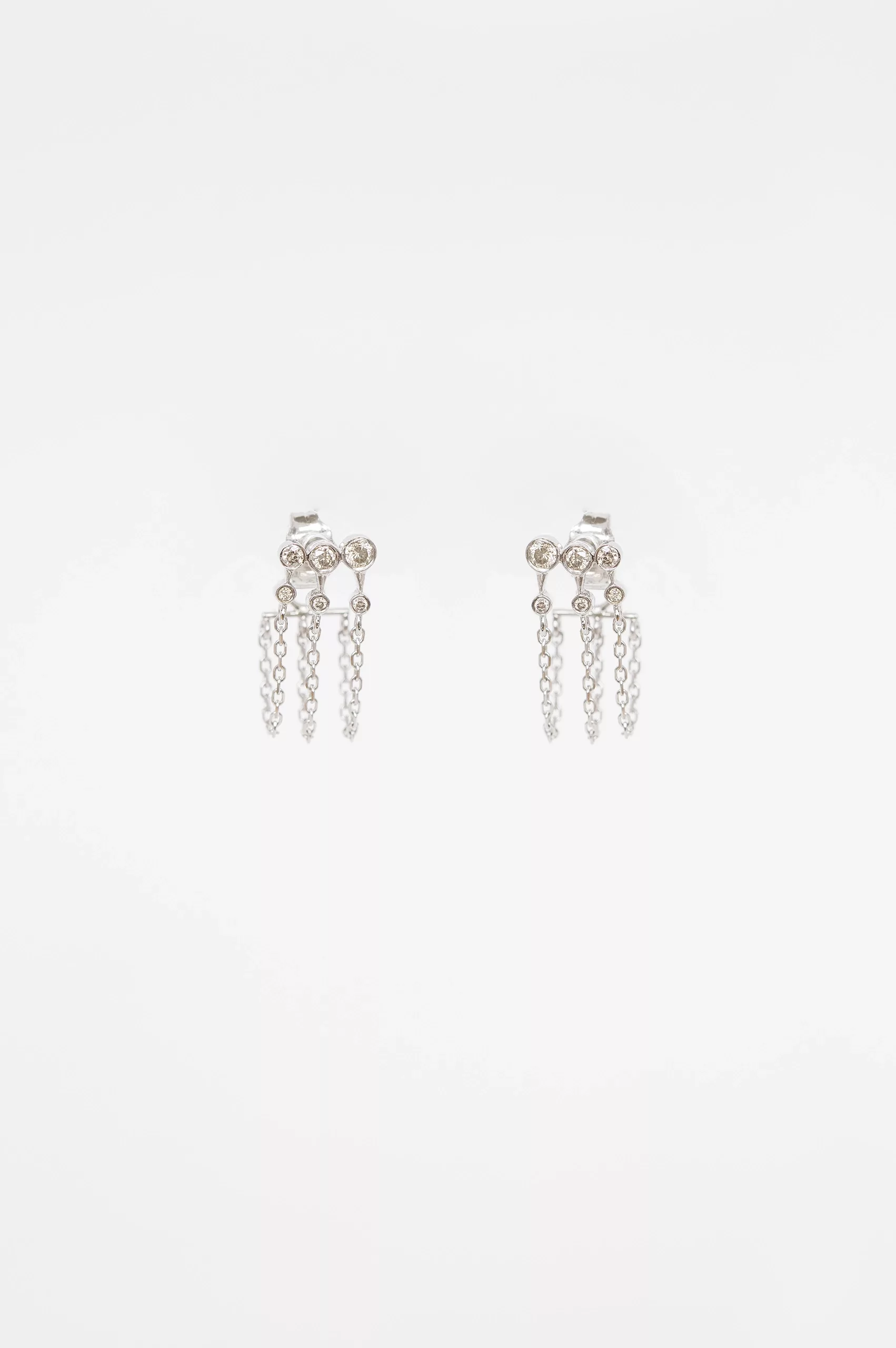 white gold chain earrings with three diamond constellation clusters set along a delicate chain, worn as an ear crawler