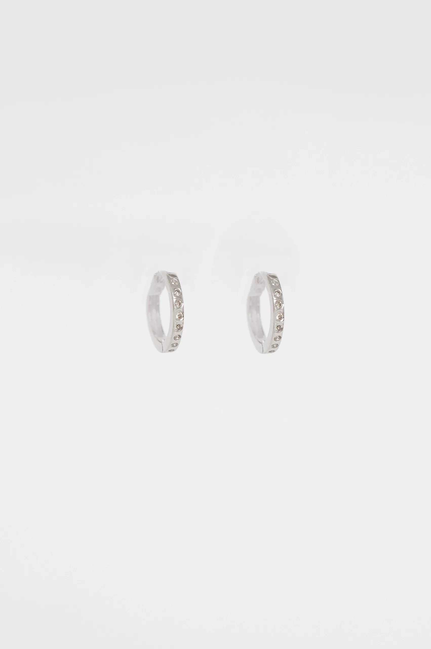white gold small hoop earrings with a continuous pavé line of round brilliant diamonds along the front of the hoop