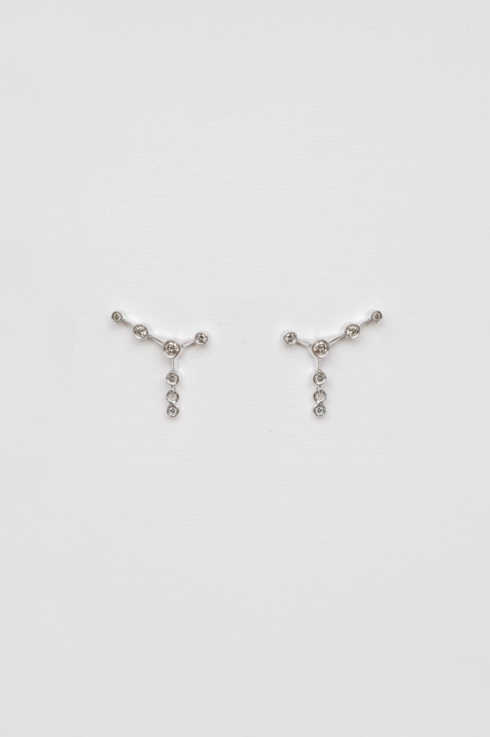 white gold ear jacket earrings featuring a constellation of diamonds along the lobe with a small dangling diamond drop below